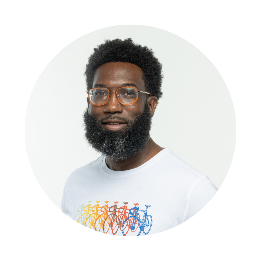 A man with orange glasses and a beard wearing a white t-shirt.